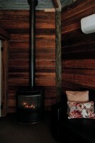 Una habitación acogedora con paneles de madera, chimenea y un sofá de cuero con un cojín floral.