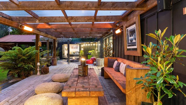Une terrasse en bois dotée d’un espace abrité, de sièges et de plantes en pot.