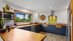 Une cuisine moderne avec un plan de travail en bois, des appareils électroménagers intégrés et une vue sur la verdure.