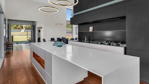 Una cocina moderna con una isla grande, armarios oscuros e iluminación colgante.
