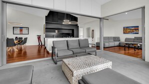 Una sala de estar moderna con un sofá gris, un otomano estampado y un comedor con una mesa y sillas.