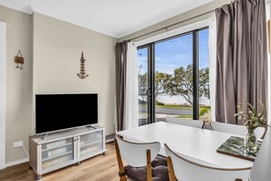 Enjoy a spacious room with a large flat-screen TV, dining table, and a window offering a view of the outdoors.
