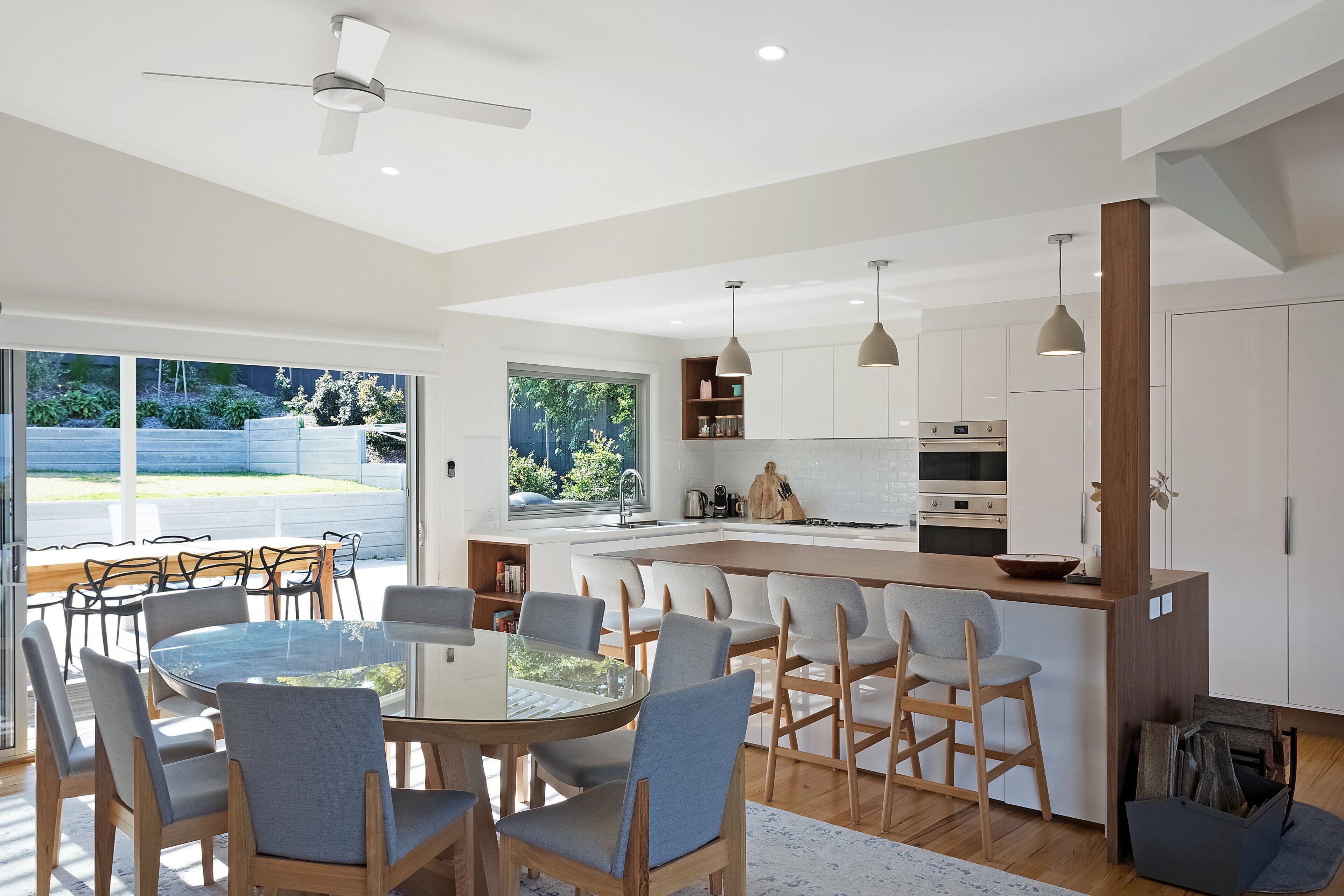 A modern kitchen with white cabinets, a wooden island, and a dining area with a glass table and chairs.