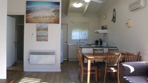 A compact kitchen with a dining area, a ceiling fan, and a beach-themed wall decoration. - Admirals Lodge: Unit 1: Pet friendly (Merimbula)