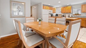 A modern kitchen with wooden cabinets, a central island, and a dining area with a wooden table and chairs. - E. Rochester Darling - Sleeps 6! (East Rochester)