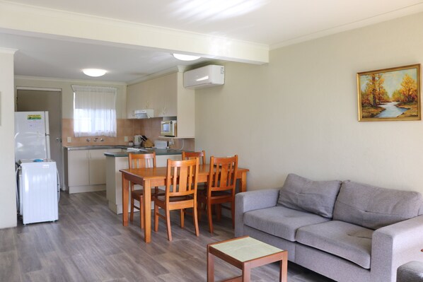 A compact living space with a kitchenette, dining area, and a sofa.