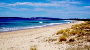 A beach with clear skies and calm waves. - Beachcomber: Unit 3 (Upstairs) (Merimbula)