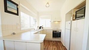 A kitchen with white cabinets, a wooden countertop, a built-in oven, and a microwave. - Beachcomber: Unit 3 (Upstairs) (Merimbula)