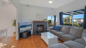Una sala de estar con televisión, chimenea, sofá y vistas al exterior.