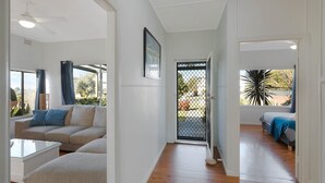 Amplia sala de estar con sofá, mesa de centro y mesa de comedor. Una puerta da acceso a un balcón con vistas al exterior.
