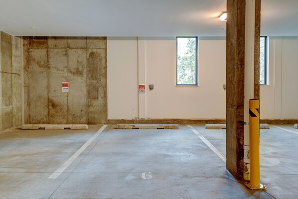A room with a concrete floor, two white doors, and a window.
