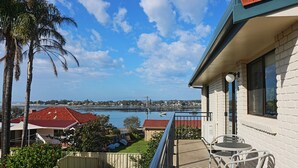 A balcony with a view of a river and a distant town. - Capri Apartments: 2 bedroom (We have 1 upstairs and one downstairs apartment) (Merimbula)