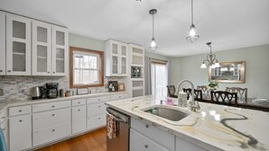 A kitchen with white cabinets, a marble countertop, and a stainless steel sink. - Poconos Peaceful Retreat. Short drive to Ski, Swim, Hike, or Shop! 4 Bedrooms. (Tobyhanna)