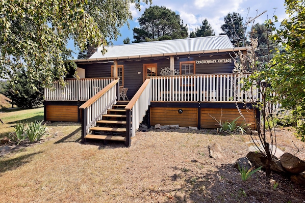 A rustic wooden cottage with a porch and wooden steps leading to a door. - Crackenback Cottage 1884: 2 bedroom (Crackenback)