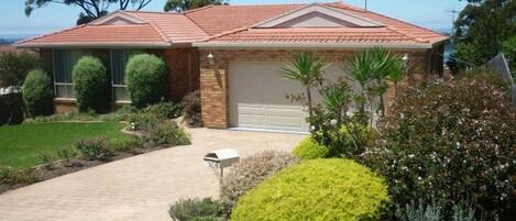 A two-story house with a red-tiled roof, a brick exterior, and a garage.