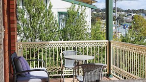 A balcony with wicker furniture and a view of a white building with green trim. - Jodi's Beach Retreat: 2 bedroom pet friendly apartment (Eden)