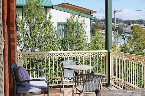 A balcony with wicker furniture and a view of a white building with green trim.
