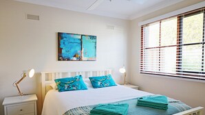 A bedroom with a bed, two nightstands, a window with blinds, and a painting on the wall. - Jodi's Beach Retreat: 2 bedroom pet friendly apartment (Eden)