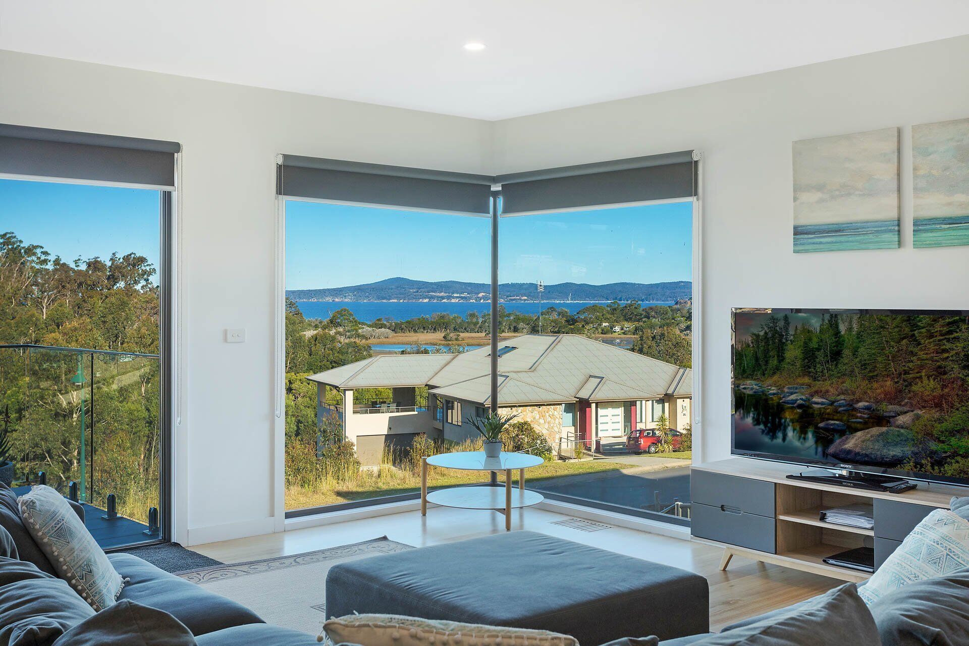 A modern living room with a large sliding glass door leading to a balcony with a scenic view.