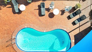 Ein Dachpool mit Terassenfliesen, umgeben von Liegestühlen und Tischen.