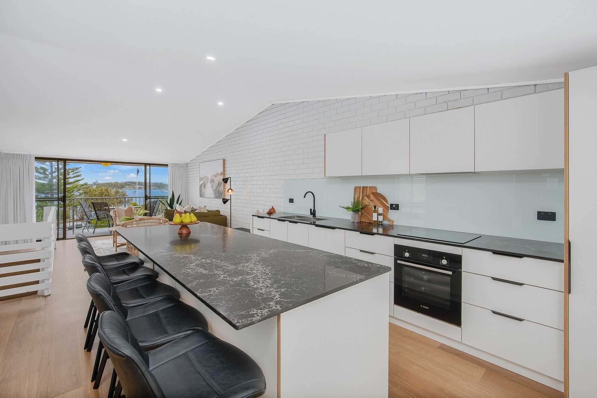 A modern kitchen with a central island, black countertops, and white cabinetry.