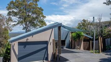 A modern garage with a sloped roof, a closed garage door, and a covered driveway area.