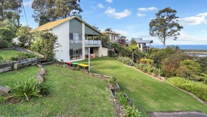 A modern two-story house with a balcony, surrounded by a well-maintained garden and a view of the sea. - Rosies Seaview - 3 bedroom option (Merimbula)