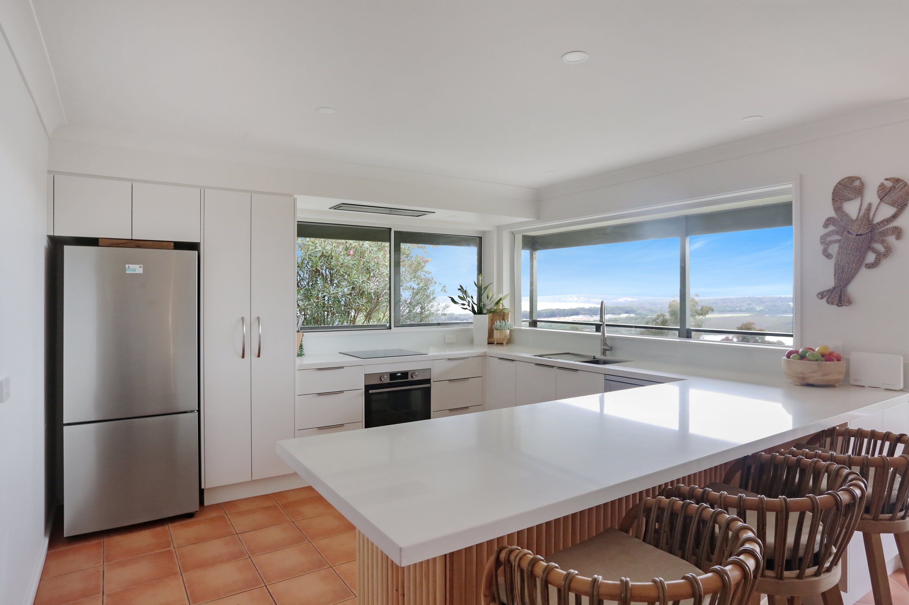 A modern kitchen with a large island, white cabinetry, and a view of the outdoors.