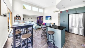 Une cuisine moderne dotée d’un îlot central, de tabourets de bar et d’un réfrigérateur en acier inoxydable.