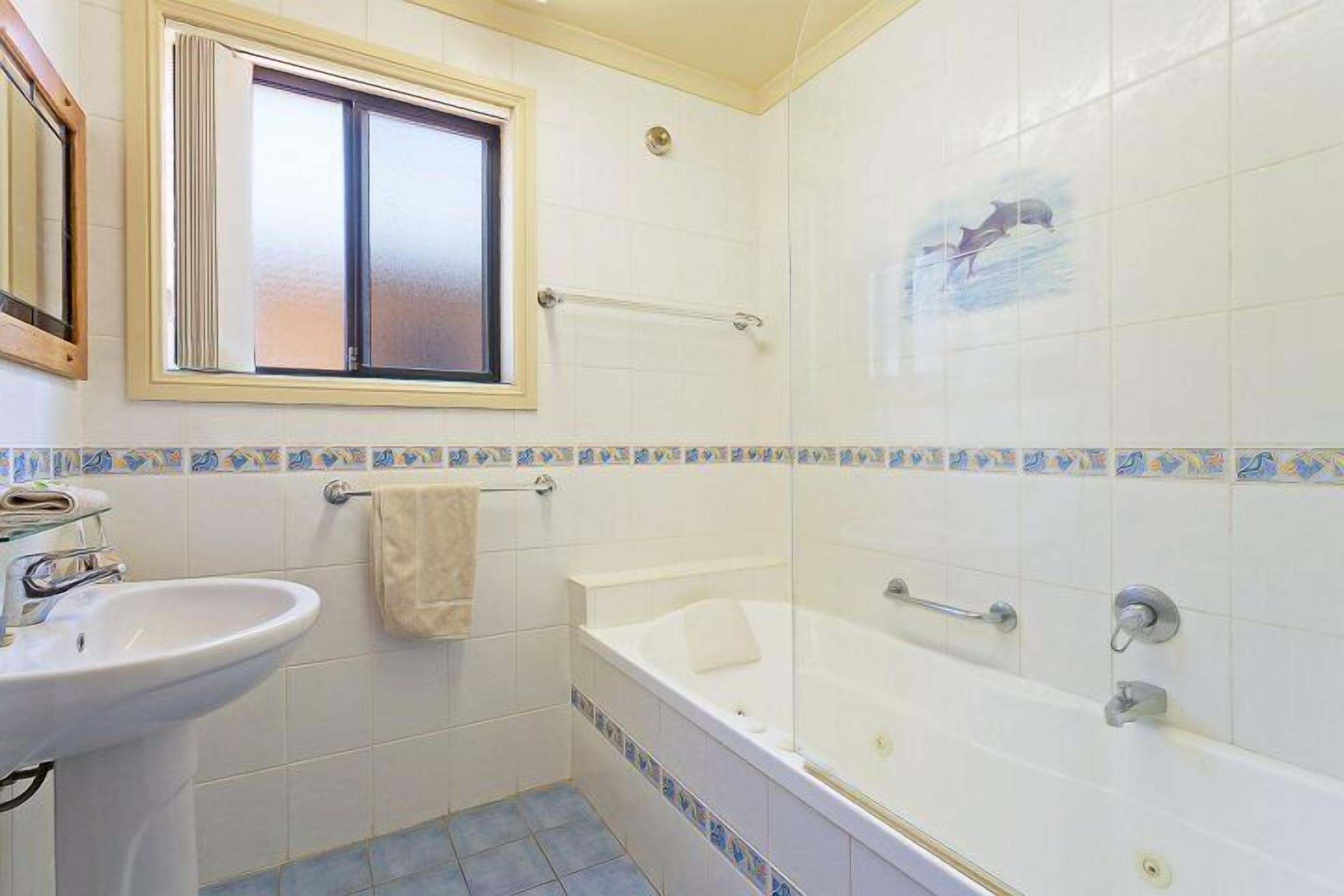 Een badkamer met een wastafel, een bad en een raam.