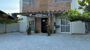 A residential building with a brick facade, large windows, and a wooden pergola entrance.
