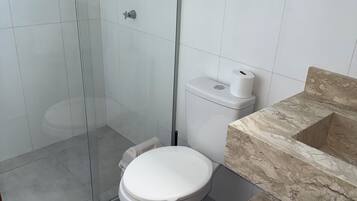 Une salle de bain moderne avec une douche à parois de verre, des toilettes et un lavabo en marbre.