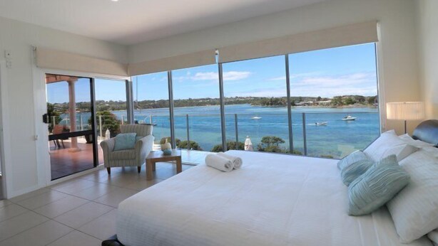 A spacious bedroom with a large bed, a view of the sea, and a balcony with a chair and table. - Sybella - 6 Bedroom Option incredible views and a pool (Merimbula)