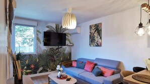Un salon moderne avec un canapé bleu, une table basse et un téléviseur fixé au mur.