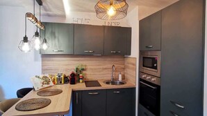 Une cuisine moderne avec des meubles de couleur sombre, un plan de travail en bois et un sol carrelé à motifs.
