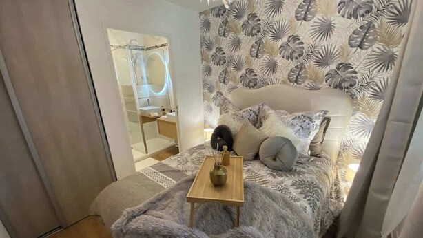 Une chambre à coucher avec un lit, une table de chevet et un miroir.