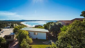 A coastal property with a view of the ocean, surrounded by greenery and a small building.