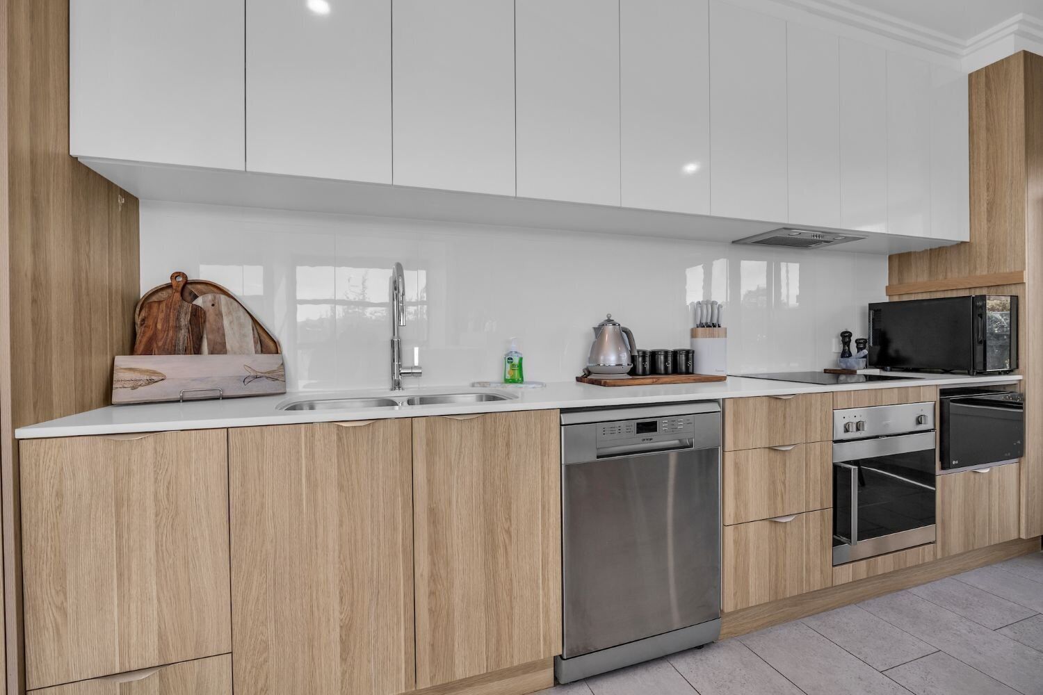 A modern kitchen with white cabinets, stainless steel appliances, and a wooden countertop.