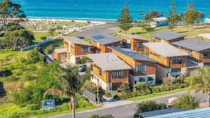 A coastal residential area with modern buildings, a road, and a view of the sea. - Shore Break 5: Unlimited wifi and right at the beach (Eden)