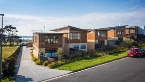 Una zona residencial moderna con casas de dos pisos, grandes ventanales y un césped bien cuidado.