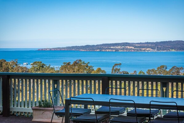 Une terrasse avec une table et des chaises offrant une vue sur la côte.