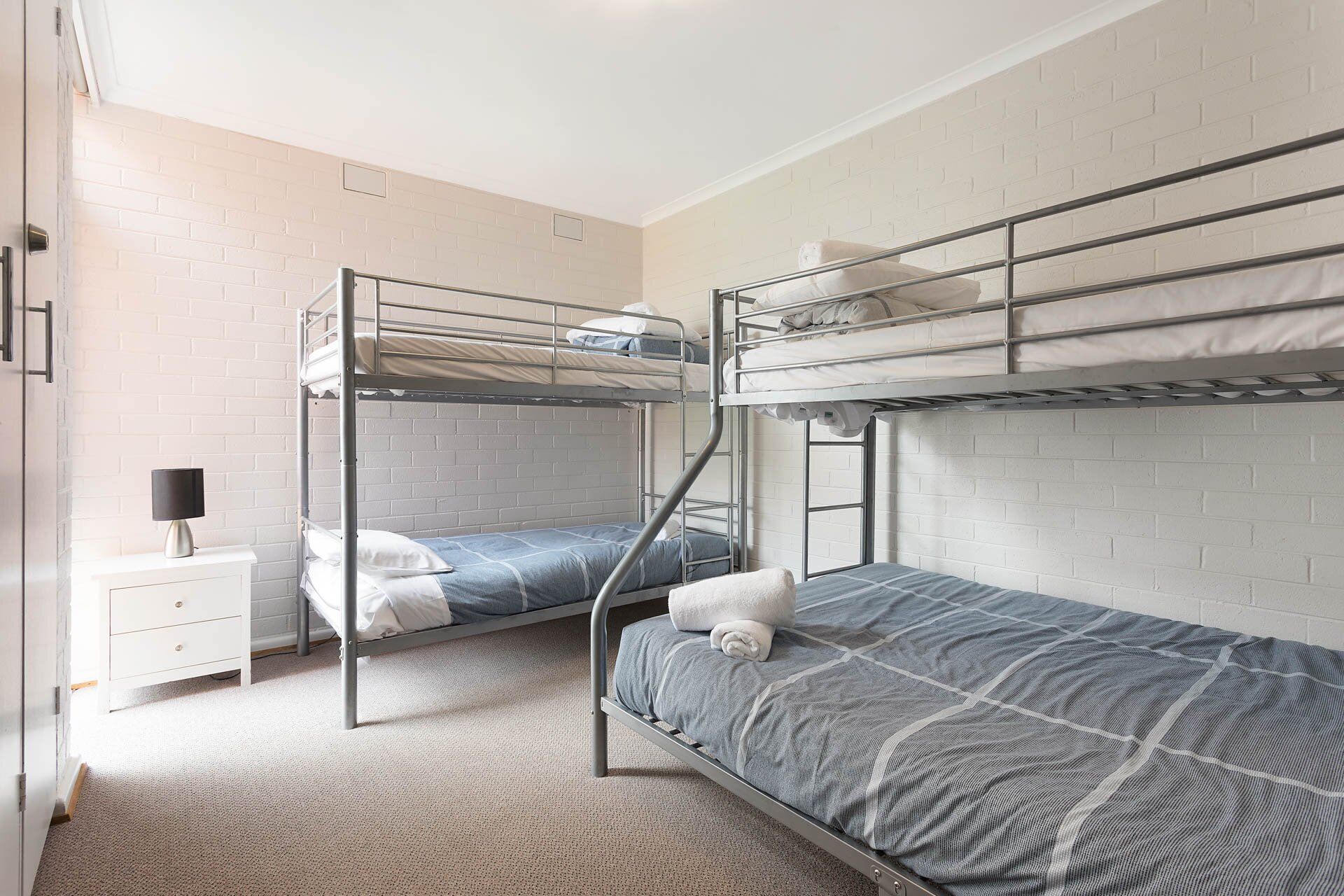 A bunk bed room with a white drawer unit and a lamp.