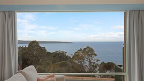 Habitación con un ventanal que ofrece vistas a un lago y terreno lejano.