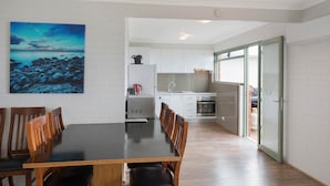 Una cocina moderna con gabinetes blancos, extractor de acero inoxidable y horno integrado.