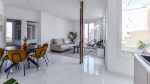 Un salon moderne comprenant un coin repas, un canapé, une table basse et une grande fenêtre.