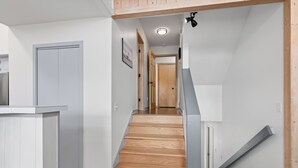 A staircase leading to a second floor, a kitchen area, and a door with a picture on the wall. - Savor the morning light from the decks and porches; close to lighthouse and ferry (Bald Head Island)