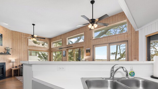 A modern kitchen with a large island, two ceiling fans, and large windows. - Savor the morning light from the decks and porches; close to lighthouse and ferry (Bald Head Island)