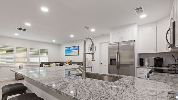 A modern kitchen with a large island, stainless steel appliances, and a view of the living area.