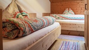 Una camera accogliente con due letti di legno, ognuno con biancheria e cuscini decorati.