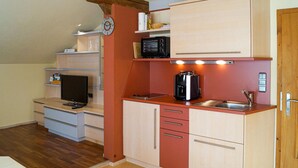 Una cucina compatta con una macchina da caffè, un tostapane e una sveglia appesa al muro.